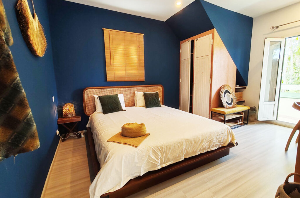 Chambre moderne avec lit double, murs bleus et lumière naturelle.