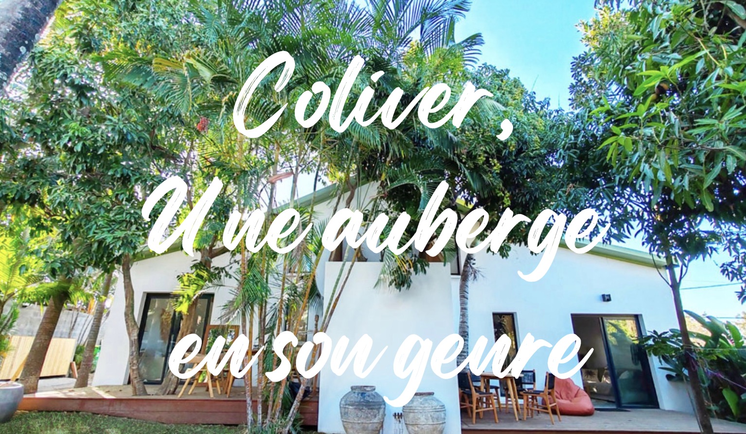 Façade d'une auberge entourée de végétation luxuriante avec texte "Coliver, une auberge en son genre".